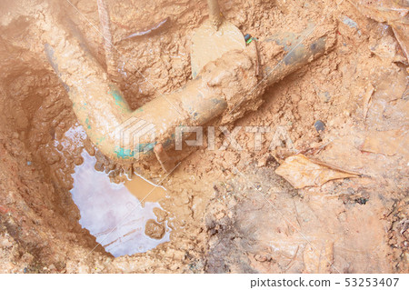 broken pipe in hole with water motion at roadside 53253407