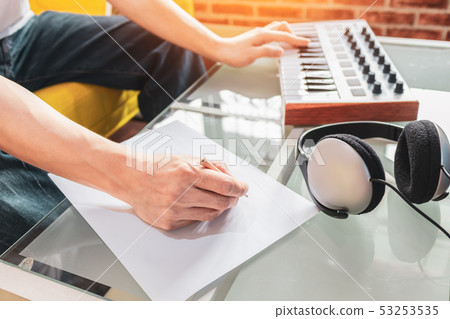 male songwriter writing a song on white paper male songwriter writing a song on white paper 53253535
