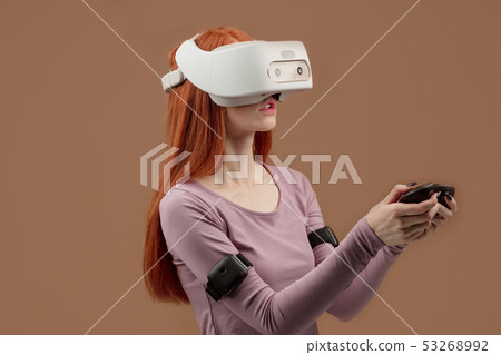 Happy young red-haired woman using a virtual reality headset Happy young red-haired woman using a virtual reality headset 53268992