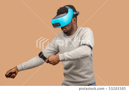 Black man wearing 3d vr glasses, playing videogame, holding joystick in hands 53283385