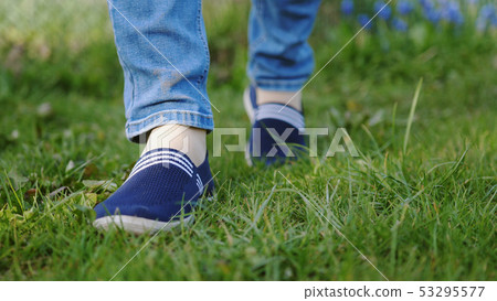 young man in red sneakers goes on a meadow 53295577