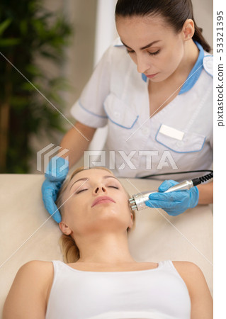 Female dermatologist providing anti-aging treatment for client 53321395