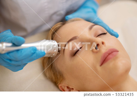 Blonde pretty businesswoman enjoying anti-aging procedures in salon 53321435