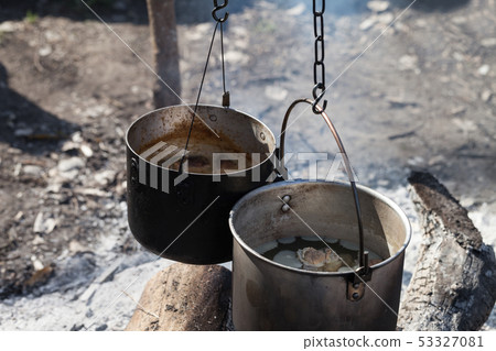 Cooking in two sooty old cauldrons on campfire 53327081