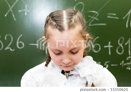 Schoolgirl teenager sad at the school blackboard. 53350620