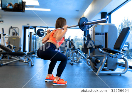 slim handsome young woman in sportswear squats 53356694