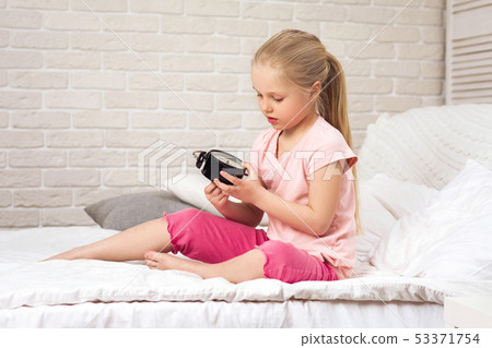little child girl in pyjamas with clock 53371754