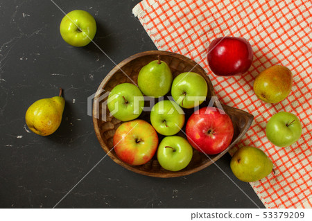 Tabletop photo - apples and pears in wooden carved bowl on black marble effect working desk with red Tabletop photo - apples and pears in wooden carved bowl on black marble effect working desk with red 53379209