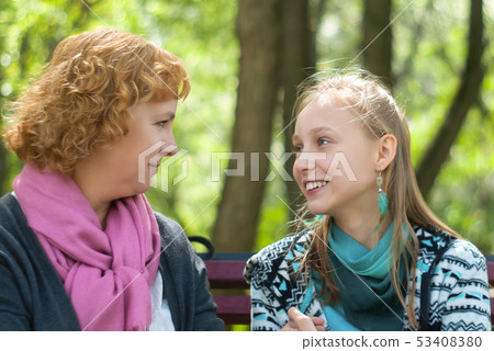 mother and teen daughter on a park bench 53408380