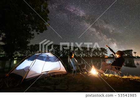 Man and woman having a rest on shore under night sky Man and woman having a rest on shore under night sky 53541985