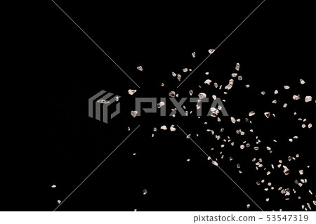 Split debris of stone exploding against black 53547319