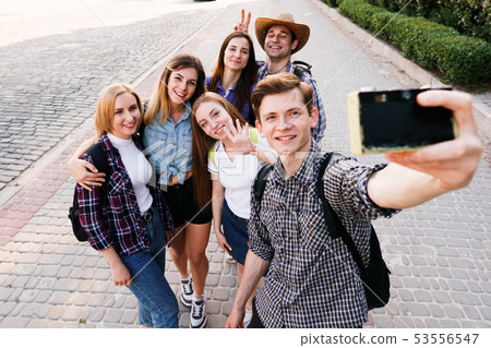 Group of friends taking selfie at camera in city Group of friends taking selfie at camera in city 53556547