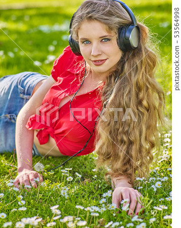 Girl in headphones catch rhythm music on green grass Girl in headphones catch rhythm music on green grass 53564998