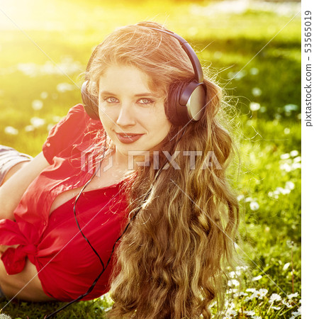 Girl in headphones catch rhythm music on green grass Girl in headphones catch rhythm music on green grass 53565019