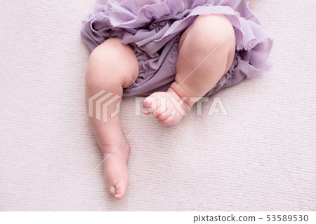 mother holds the feet of the newborn baby  53589530