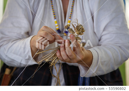 Woman in a white shirt makes a straw toy 53590802