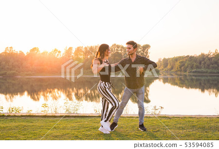 Kizomba, bachata, zouk and latin social dance concept - Man and woman dancing over nature background Kizomba, bachata, zouk and latin social dance concept - Man and woman dancing over nature background 53594085