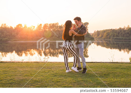 Romantic, social dance and people concept - young couple dancing bachata on the background of sunset Romantic, social dance and people concept - young couple dancing bachata on the background of sunset 53594087