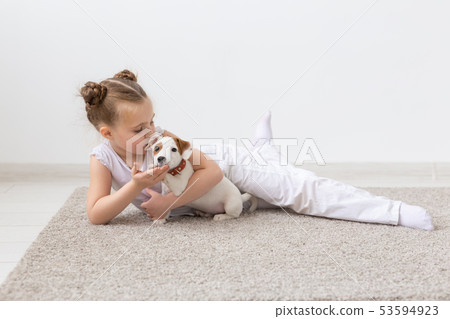 Childhood, pets and dogs concept - Little child girl posing on the floor with puppy 53594923