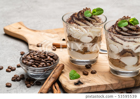 Classic tiramisu dessert in a glass on dark concrete background Classic tiramisu dessert in a glass on dark concrete background 53595539