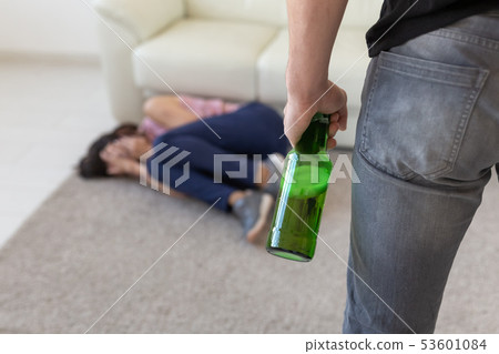 Victim, domestic violence, abuse and alcoholic concept - drunk man with bottle near his wife lying Victim, domestic violence, abuse and alcoholic concept - drunk man with bottle near his wife lying 53601084