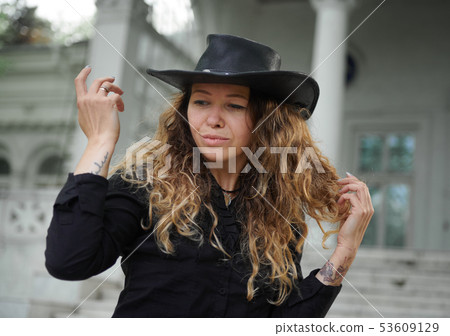 fashionable girl dressed in black shirt, hat and 53609129