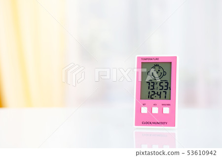 Pink electronic hygrometer on white table in front 53610942