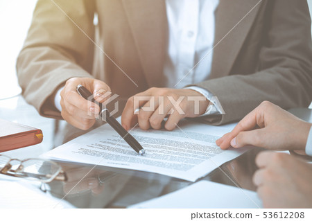 Group of business people or lawyers discussing contract papers sitting at the table, close-up Group of business people or lawyers discussing contract papers sitting at the table, close-up 53612208
