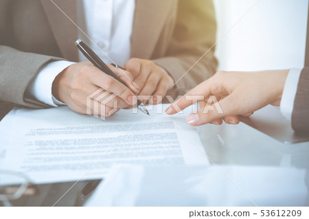 Businesswoman signing contract papers. Group of business people at meeting or negotiation, close-up 53612209