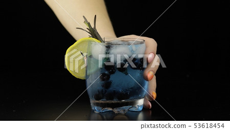 Woman hand takes refreshing soda lemonade blue cocktail Woman hand takes refreshing soda lemonade blue cocktail 53618454