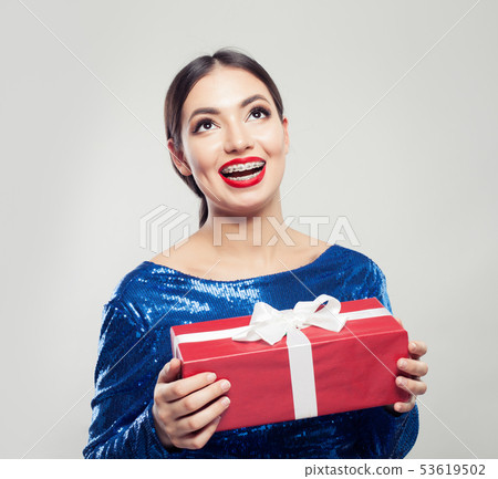 Smiling woman in braces with gift Smiling woman in braces with gift 53619502