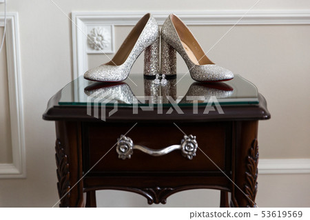 Women's wedding shoes and earrings on the bedside table 53619569