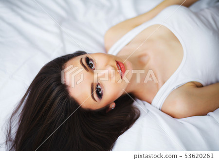 Cute woman smiling in bed on white pillow after sleep or nap Cute woman smiling in bed on white pillow after sleep or nap 53620261