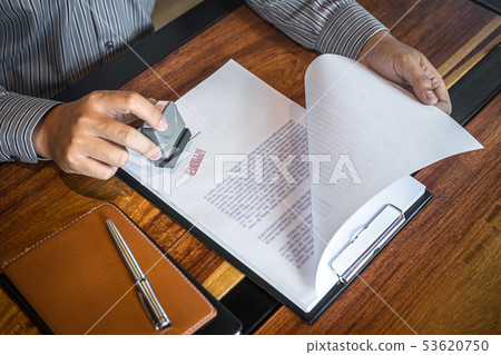 Hands of businessman stamp on paper document to 53620750