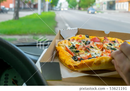 driver eats pizza in the car driver eats pizza in the car 53621191