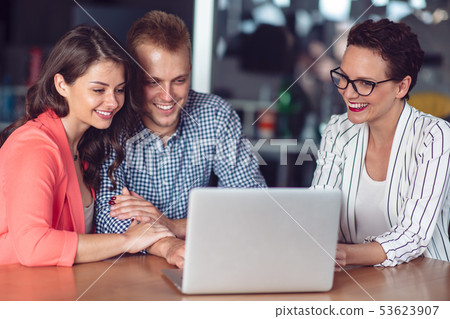 Investment adviser giving a presentation to a friendly smiling young couple seated at her desk in Investment adviser giving a presentation to a friendly smiling young couple seated at her desk in 53623907