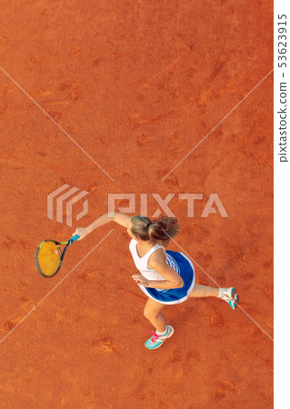 Aerial shot of a female tennis player on a court during match. Young woman playing tennis.High angle Aerial shot of a female tennis player on a court during match. Young woman playing tennis.High angle 53623915