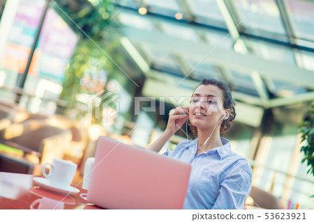 Image of happy woman using laptop while sitting at cafe. Young woman sitting in a coffee shop and 53623921