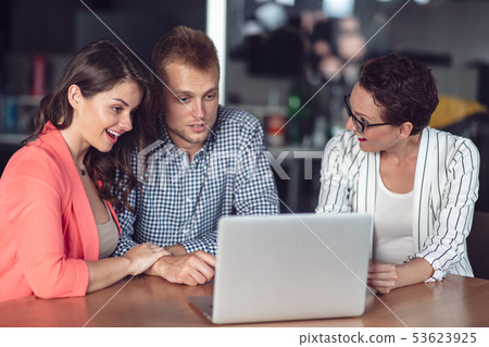Investment adviser giving a presentation to a friendly smiling young couple seated at her desk in Investment adviser giving a presentation to a friendly smiling young couple seated at her desk in 53623925