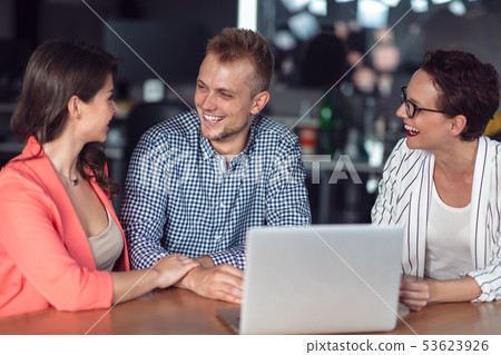 Investment adviser giving a presentation to a friendly smiling young couple seated at her desk in 53623926