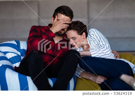 Young couple at home watching a movie with popcorn Young couple at home watching a movie with popcorn 53624319