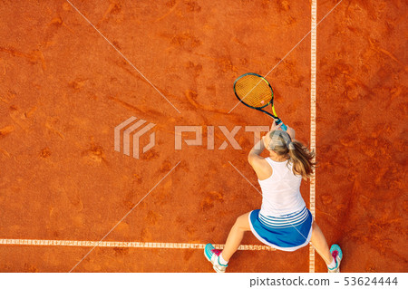 Aerial shot of a female tennis player on a court during match. Young woman playing tennis.High angle Aerial shot of a female tennis player on a court during match. Young woman playing tennis.High angle 53624444
