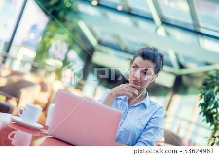 Image of happy woman using laptop while sitting at cafe. Young woman sitting in a coffee shop and 53624961