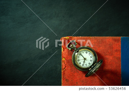 Pocket watch and old book on cement floor. Pocket watch and old book on cement floor. 53626456