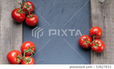 Fresh tomatoes on a branch on a dark background. Fresh tomatoes on a branch on a dark background. 53627633