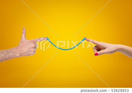 Side crop closeup of woman's and man's hands pointing fingers to each other, connected by thin 53629853