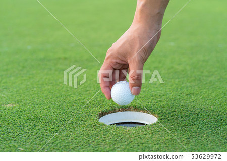 hand picking up a golf ball from the fairway 53629972