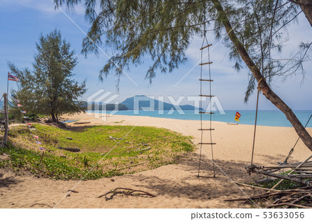 Natural tropical sandy beach and calm sea landscape with trees and blue sky background. Mai Khao Natural tropical sandy beach and calm sea landscape with trees and blue sky background. Mai Khao 53633056