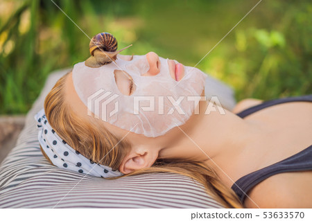 Young woman makes a face mask with snail mucus. Snail crawling on a face mask 53633570