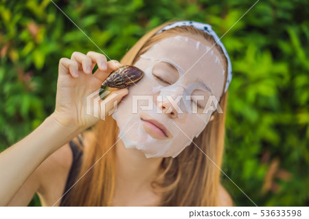 A young woman makes a face mask with snail mucus. Snail crawling on a face mask 53633598